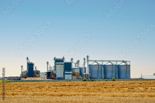 Obraz na płótnie Grain silos, agriculture and industry, with towering grain silos and lush wheat field. Silos granary elevator, industrial complex for grain storage. Storage facilities in the agricultural supply chain w salonie