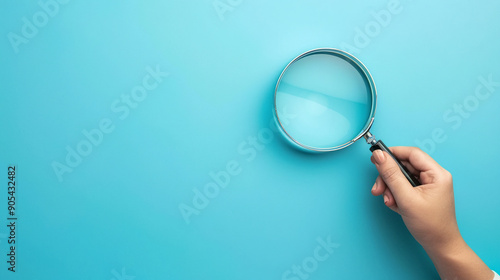 Person holding magnifying glass on blue background. Copy space photo