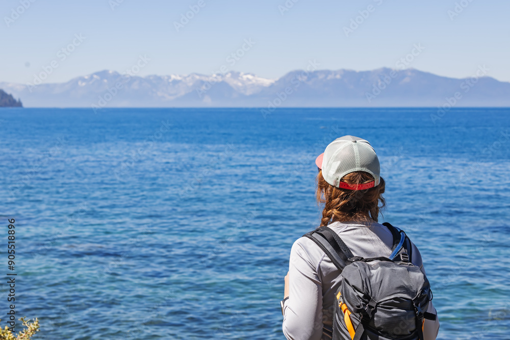 Woman hiker Observing Scenic View of the lake Tahoe With Mountains on the background Woman hiker Observing Scenic View of the lake Tahoe With Mountains on the background