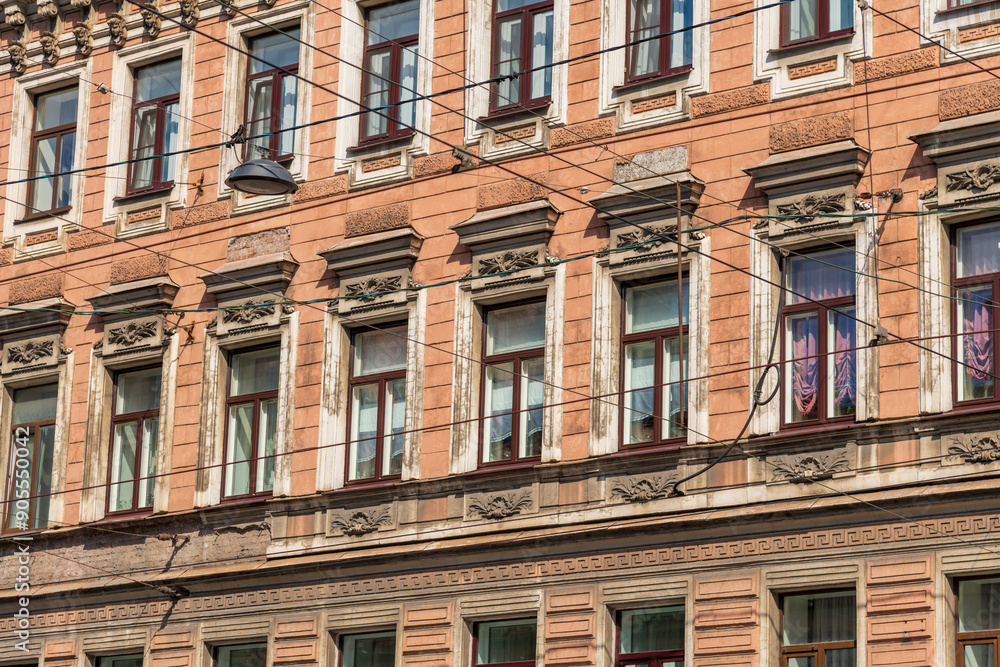 Side view of traditional ornate brown coloured facade with group of windows on wall of residential building in Saint Petersburg, Russia. Copy space. Architecture and city street background theme. Side view of traditional ornate brown coloured facade with group of windows on wall of residential building in Saint Petersburg, Russia. Copy space. Architecture and city street background theme.