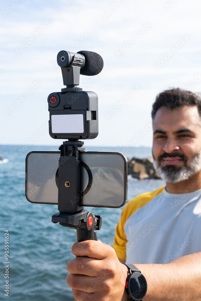 Man recording a video at seaside using modern gadgets Man recording a video at seaside using modern gadgets