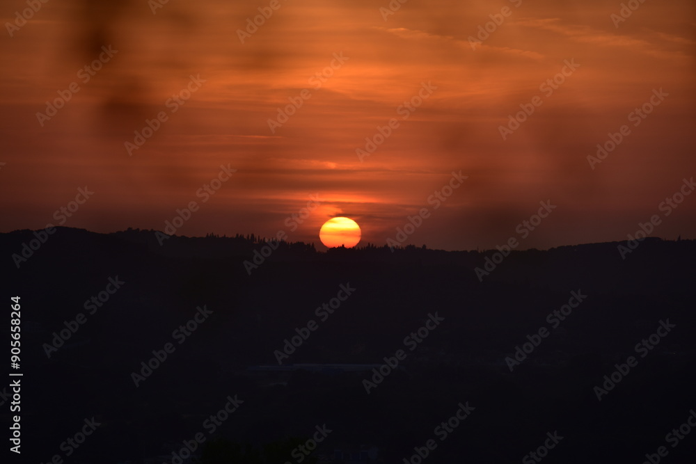 Epic sunset landscape sky with big bright sun going behind the mountains in Greece Epic sunset landscape sky with big bright sun going behind the mountains in Greece