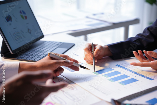 Business team discussing and analyzing financial documents with charts and graphs using a laptop computer during a meeting