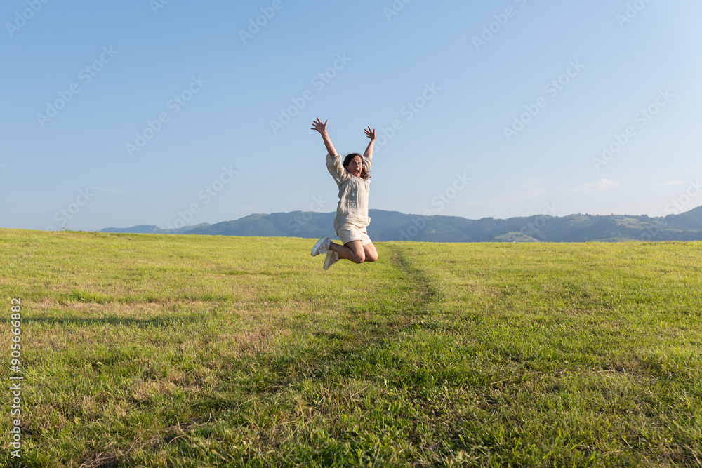 Woman joyfully jumping in a vast green field Woman joyfully jumping in a vast green field