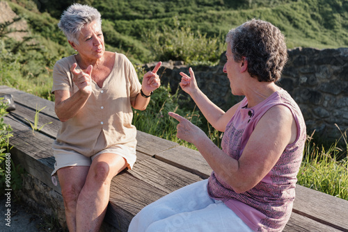 Senior deaf women communicating through sign language outdoors
