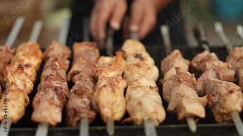 Male hands rotate shish kebab on brazier, cooking outdoors. Side slide motion