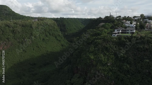 Gigantic tropical valley in suburbs of Mauritius, houses perched on cliffs, stunning cinematic aerial drone video