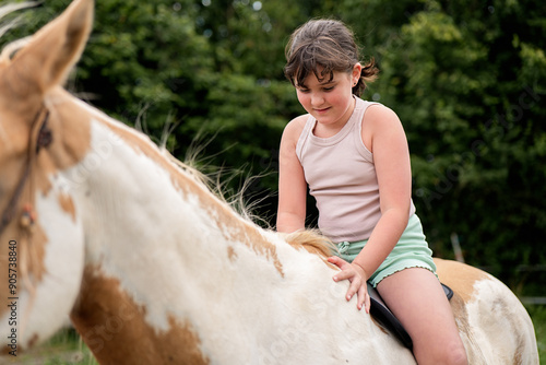 Young girl riding a paint horse in a natural setting photo