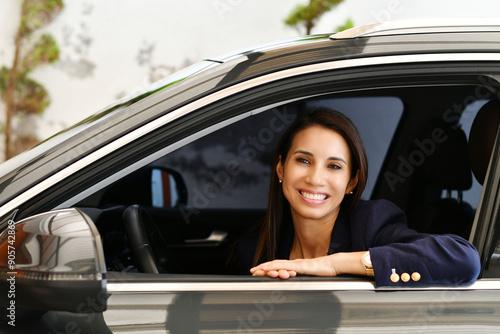 Mujer joven adulta feliz por la compra de su auto nuevo, sonriente en la ventana del vehículo nuevo.