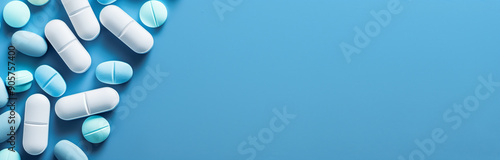 Scattered pills on a plain blue background representing mental health medication pharmaceutical industry and healthcare with copy space for text