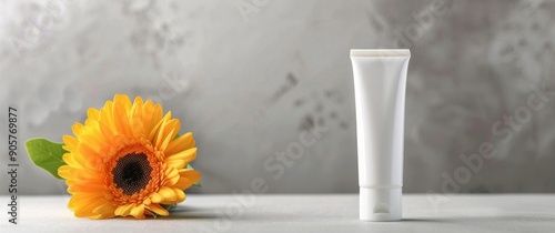 White Cream Tube Beside Bright Yellow Flowers on Grey Surface