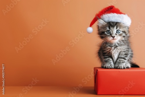 Adorable Kitten Wearing Santa Hat Sitting on Red Gift Box