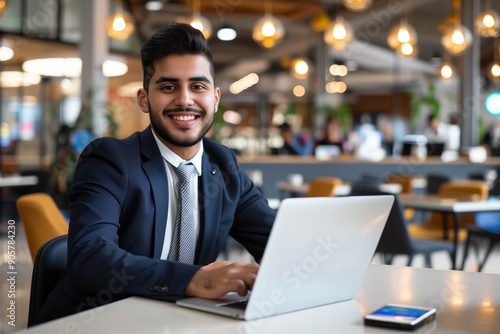 Young smiling businessman working on his laptop wearing navy suit