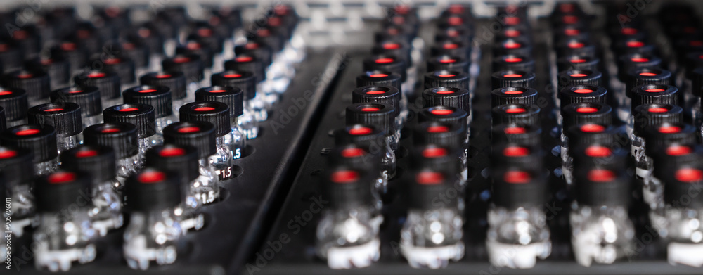 Obraz premium HPLC glass vials with black caps in the auto sampler are waiting for injection. 