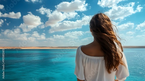 A beautiful young woman looks at the beautiful sea, clouds and mainland in the far distance the Red Sea 