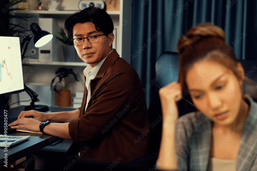 Serious face of thinking businesswoman focusing computer to report data analysis social media online project job with coworker working at back side at over late night time at modern office. Infobahn. Serious face of thinking businesswoman focusing computer to report data analysis social media online project job with coworker working at back side at over late night time at modern office. Infobahn.