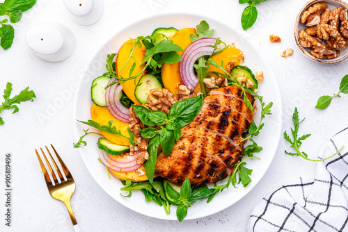 Fresh healthy eatung salad with peaches, chicken, cucumber, nuts, onion, basil and arugala, white background, top view photo