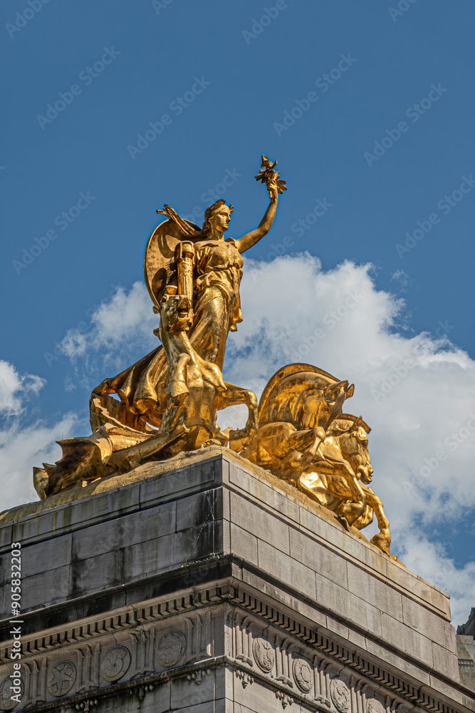 Obraz premium New York, NY, USA - August 2, 2023: Maine monument golden statue closeup on SW corner Central Park under blue cloudscape