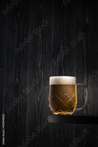 A frosty cold glass of light beer on a black wooden table photo