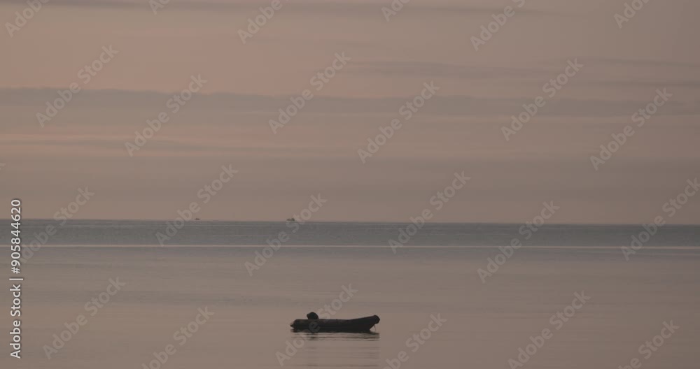 Single inflatable boat dinghy floating on calm ocean water distant horizon dawn Single inflatable boat dinghy floating on calm ocean water distant horizon dawn