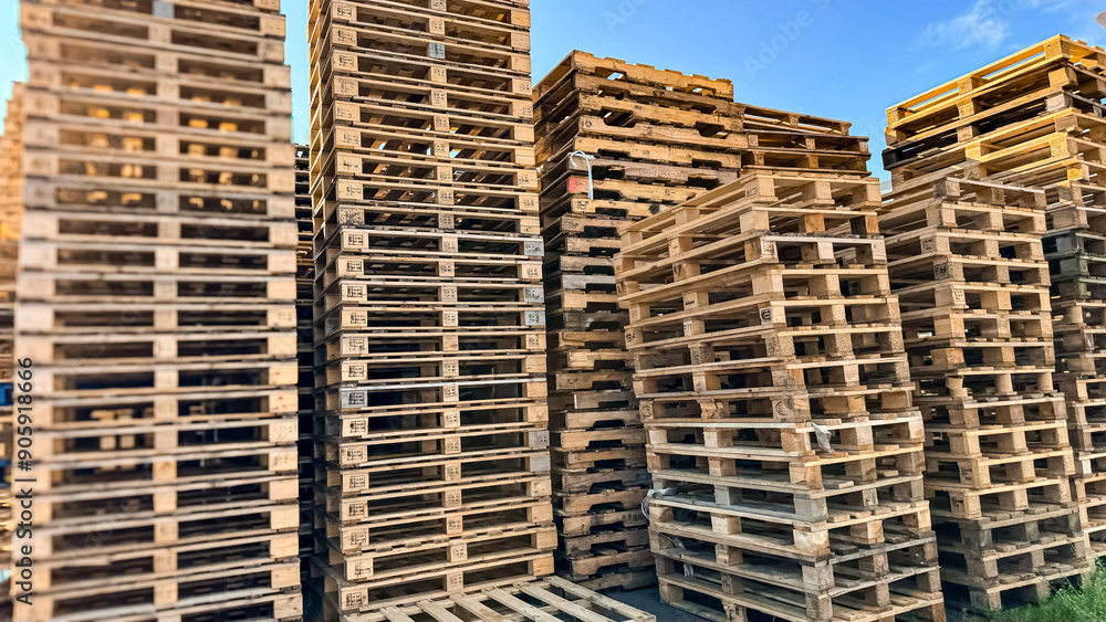 Wooden pallets. Factory and carefully arranged tall stacks of wooden pallets, ready for transportation and logistics Wooden pallets. Factory and carefully arranged tall stacks of wooden pallets, ready for transportation and logistics