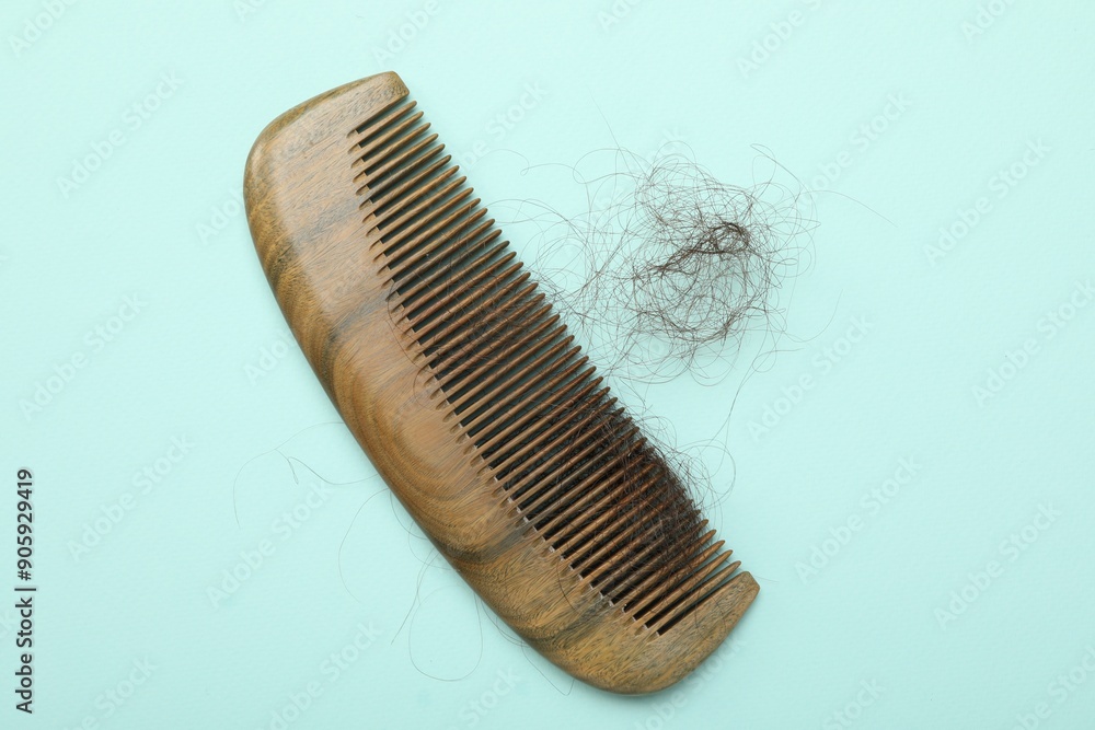 One comb with lost hair on light blue background, top view. Alopecia problem One comb with lost hair on light blue background, top view. Alopecia problem