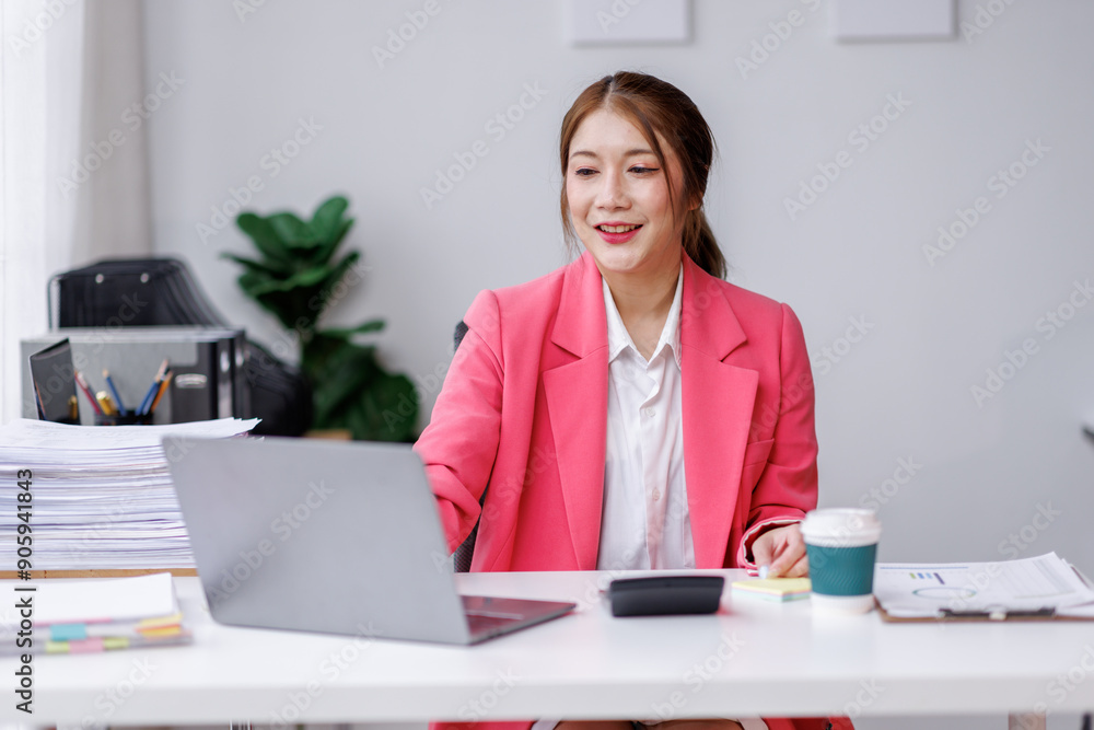 Young attractive business asian woman working of reading paper accounting file financial report, tax invoice on her documents project with laptop computer in the workplace office.