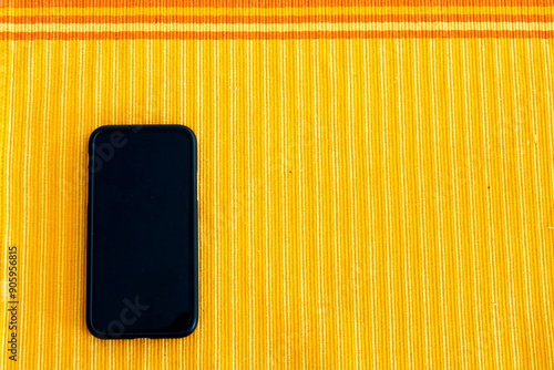 A black smartphone on a yellow striped background photo