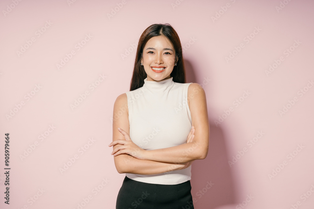 Obraz premium Confident Young Woman in White Sleeveless Top Smiling Against Pink Background
