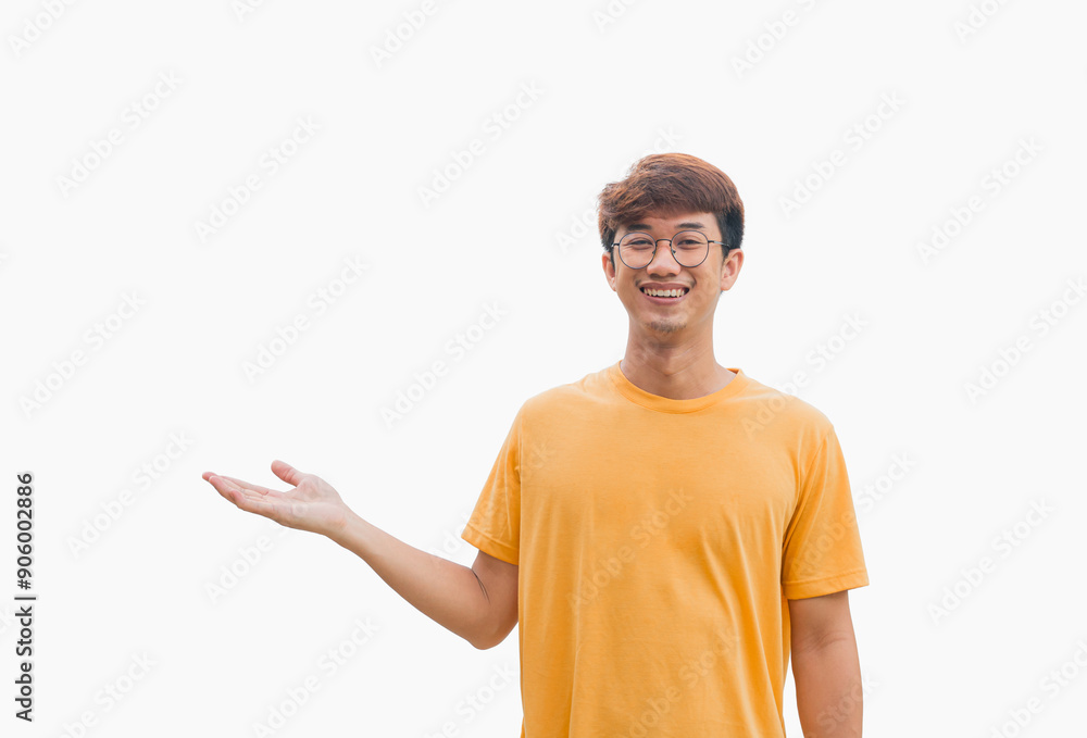 A young Asian man in his 20s wearing a yellow t-shirt making a welcome gesture or presenting isolated on a gray background. Space for advertisements or welcome messages. Happy man. Positive person. A young Asian man in his 20s wearing a yellow t-shirt making a welcome gesture or presenting isolated on a gray background. Space for advertisements or welcome messages. Happy man. Positive person.