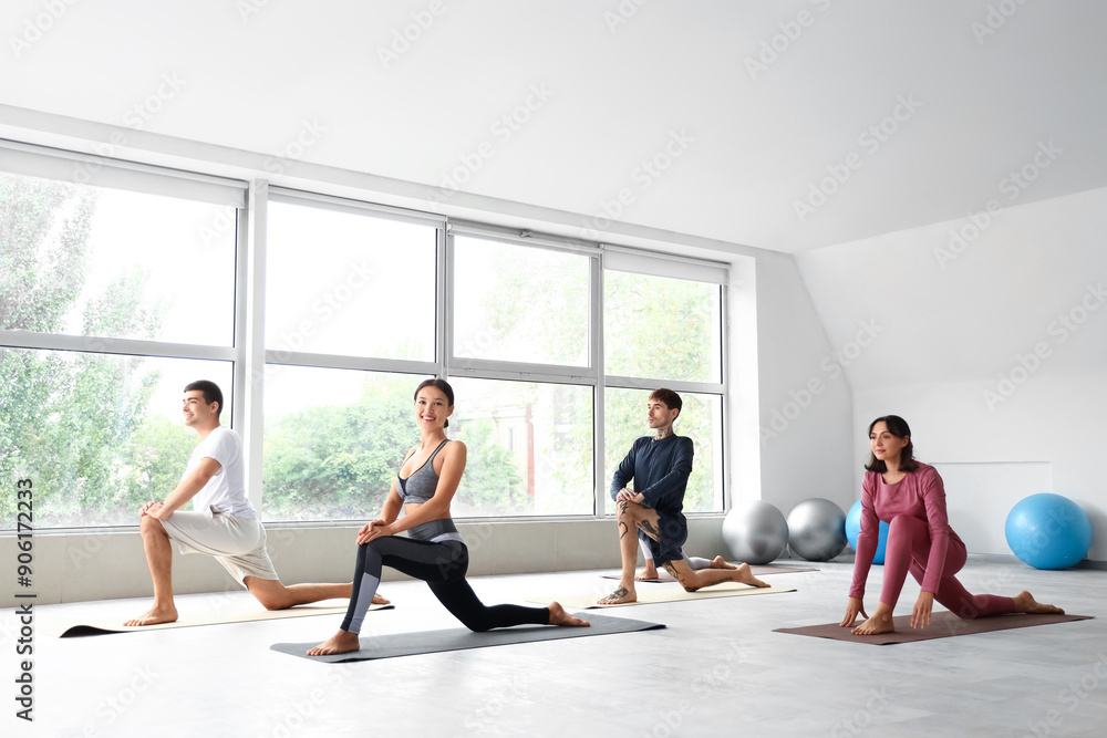 Obraz premium Group of sporty young people practicing yoga in gym