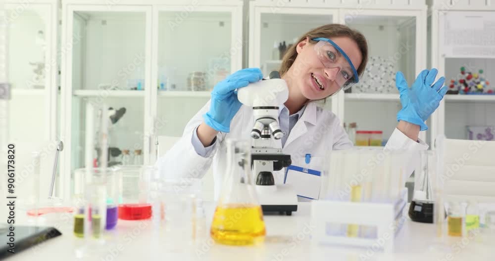 Woman researcher examines sample using modern microscope. Scientist adjusts magnification of microscope to improve visibility of sample Woman researcher examines sample using modern microscope. Scientist adjusts magnification of microscope to improve visibility of sample