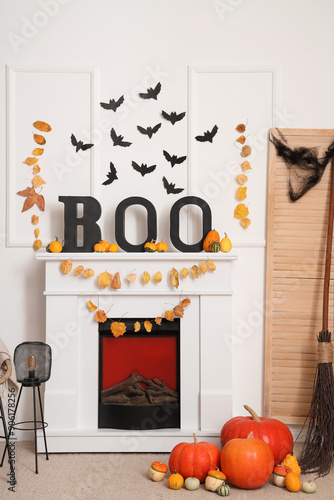 Interior of living room decorated for Halloween with fireplace, autumn leaves and paper bats