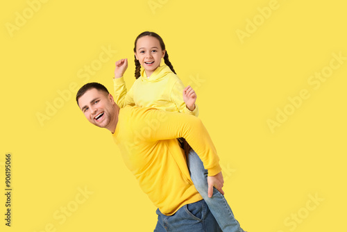 Father playing with his daughter on yellow background © Pixel-Shot