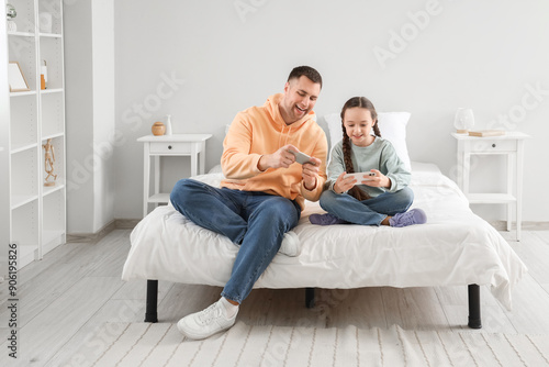 Father and his daughter with smartphones in bedroom © Pixel-Shot