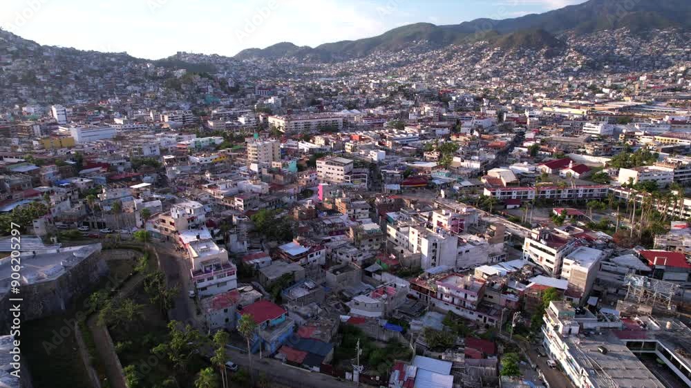 Backwards scenic flight over residential area in Acapulco with crowded cityscape, mountains and coastal road Backwards scenic flight over residential area in Acapulco with crowded cityscape, mountains and coastal road