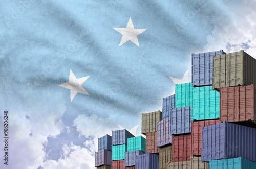 Micronesia flag and big stack of shipping cargo containers in docks with sky background close up photo