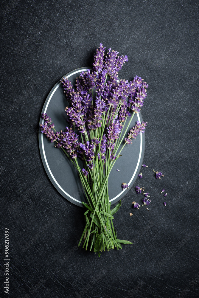 Bunch of fresh lavender flowers arranged on a plate over dark textured background.
