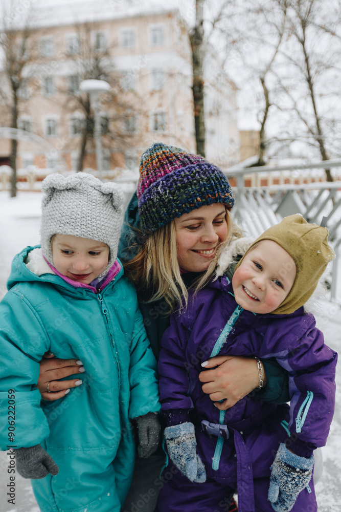 Happy family in warm clothes smiling at camera while playing on fresh air in winter snowy forest Happy family in warm clothes smiling at camera while playing on fresh air in winter snowy forest