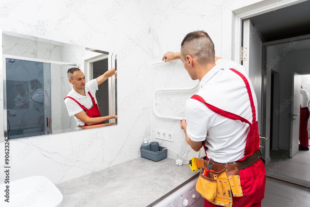 Male plumber sets electric towel dryer for bathroom. Male plumber sets electric towel dryer for bathroom.