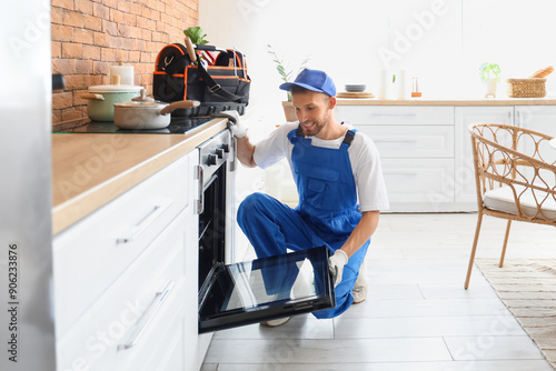 Fotografie Male technician checking broken oven in kitchen