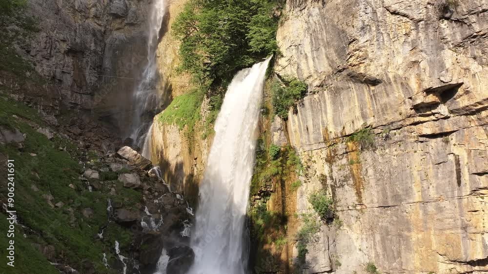 Drone slowly pans left to right over Seerenbachfälle waterfalls, cascading with great force and sunlight on a sunny day in Amden Betlis, Walensee, Switzerland. Drone slowly pans left to right over Seerenbachfälle waterfalls, cascading with great force and sunlight on a sunny day in Amden Betlis, Walensee, Switzerland.