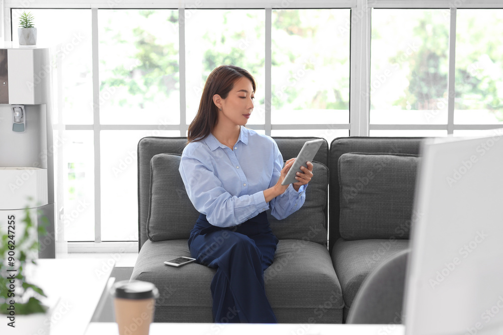 Asian businesswoman working with tablet computer on sofa in office Asian businesswoman working with tablet computer on sofa in office