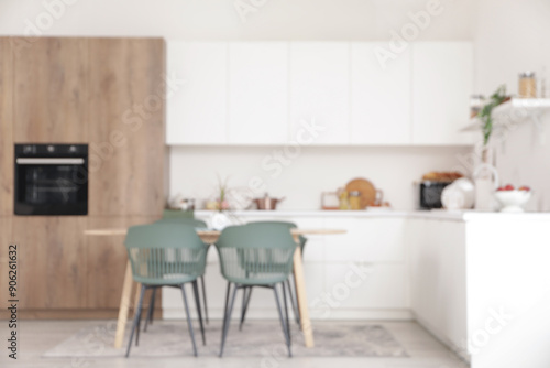 Blurred view of light kitchen with counters and dining table