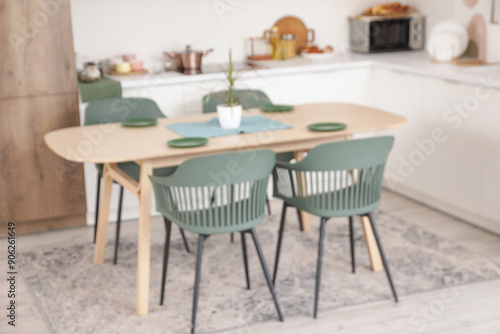 Blurred view of light kitchen with counters and dining table