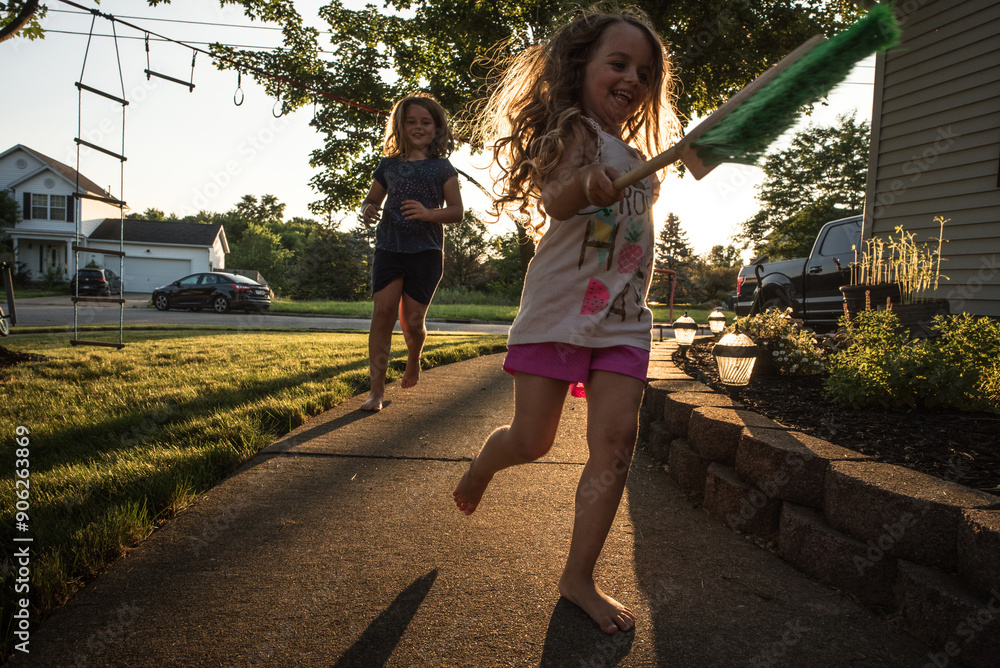 © Cavan Images - Young sisters playing tag outside on sunny summer evening
