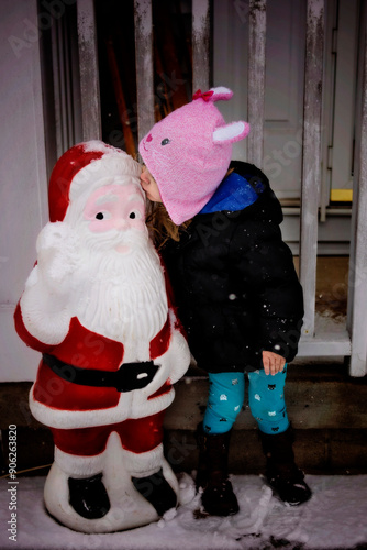 Young girl kissing Santa decoration outdoors photo