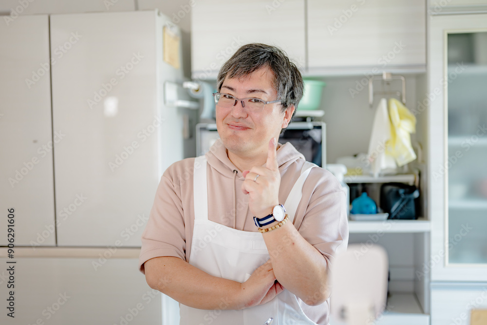 キッチンで人差し指を立てる中年男性 キッチンで人差し指を立てる中年男性