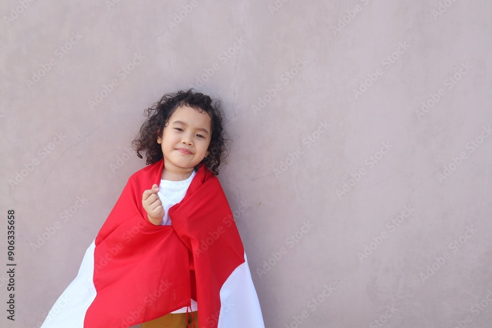 Portrait of a girl wearing the red and white Indonesian flag with an adorable expression to celebrate Indonesia's independence.