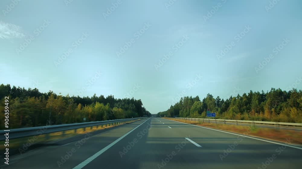 View through rear windshield windscreen of car in motion, back glass screen. Dual carriageway with two-lane road along forest. Countryside roadway out of town. Travel journey. Traffic crash barrier View through rear windshield windscreen of car in motion, back glass screen. Dual carriageway with two-lane road along forest. Countryside roadway out of town. Travel journey. Traffic crash barrier
